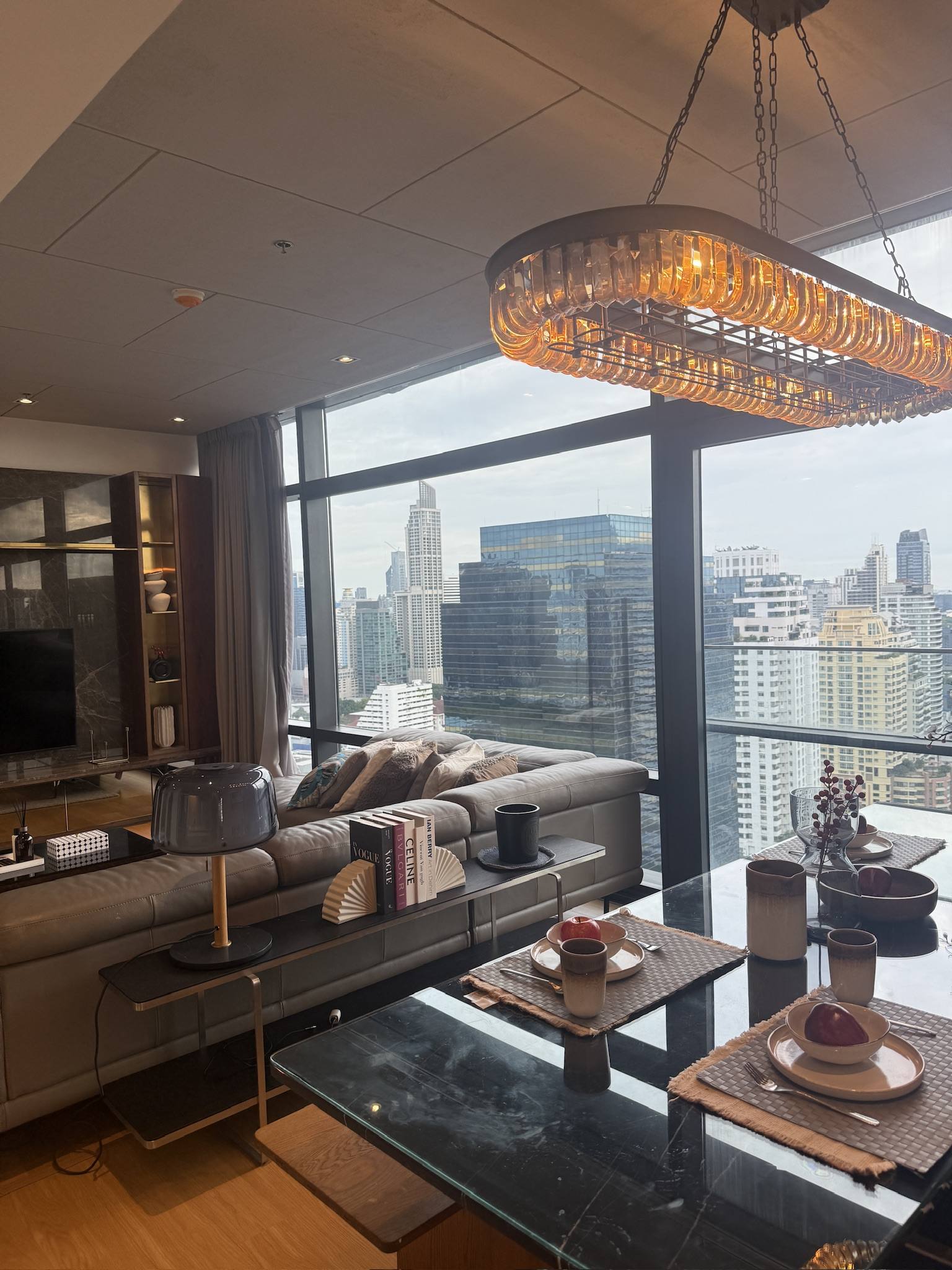 A city apartment living room at dusk, skyline through the window