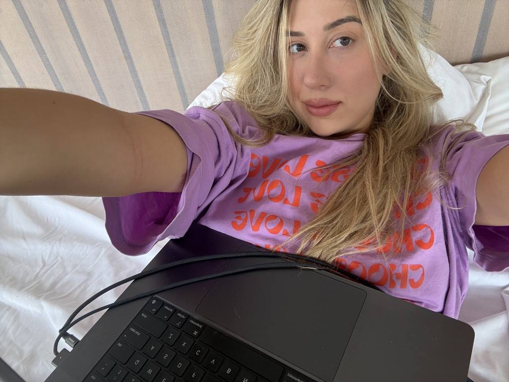 Working from bed with a laptop, pink graphic tee