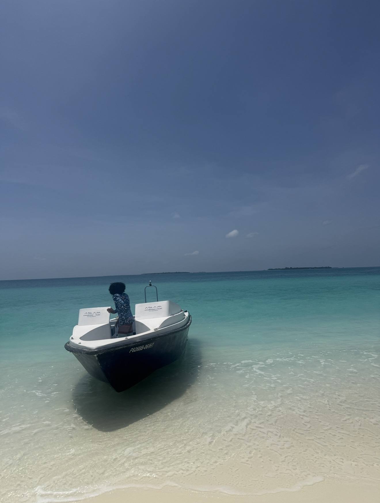 A boat moored off a sandbank, clear shallow water