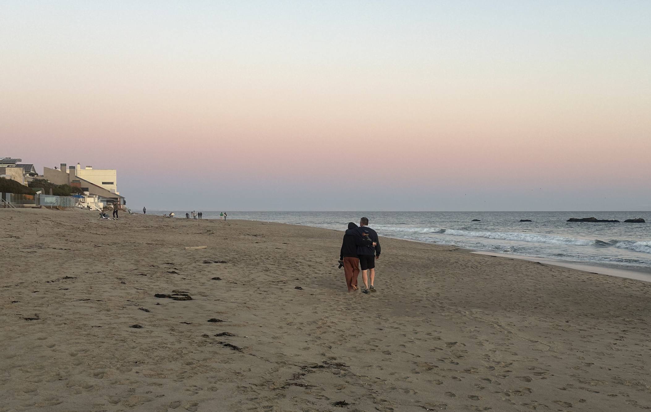 Two people walking a wide empty beach at sunset