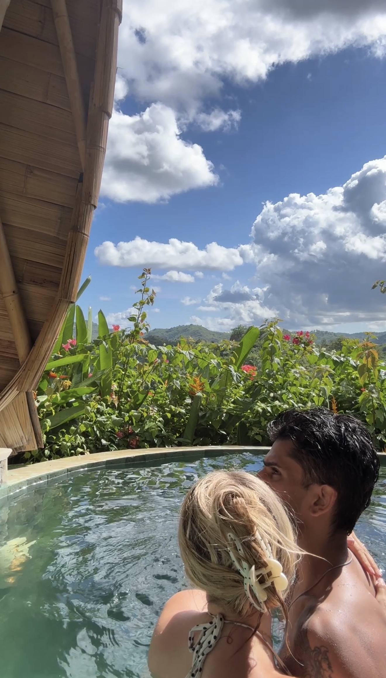 Two people in a small jungle plunge pool surrounded by green