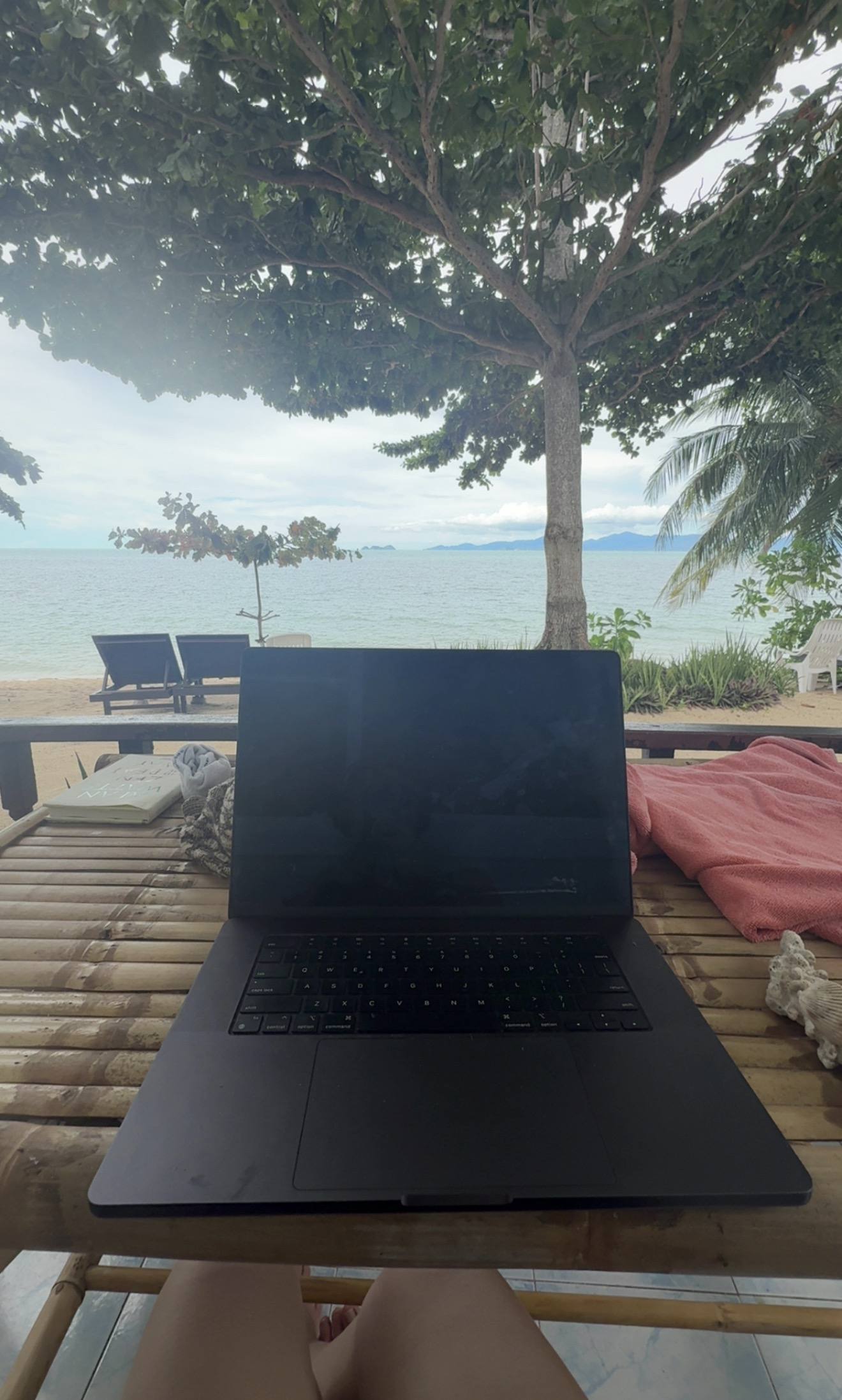 An open laptop on a lounger looking out to the sea