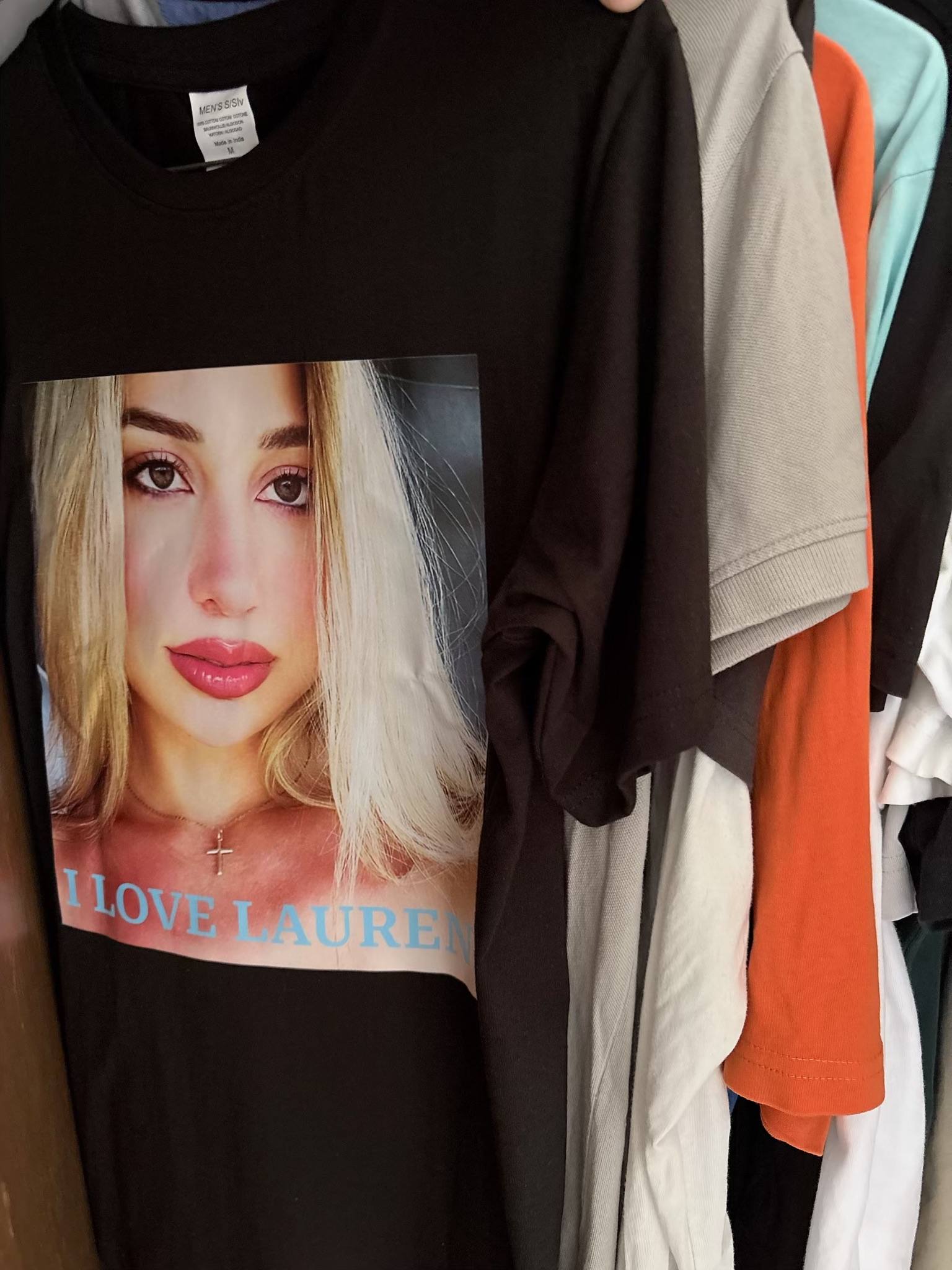 A printed tee hanging on a rail among other clothes