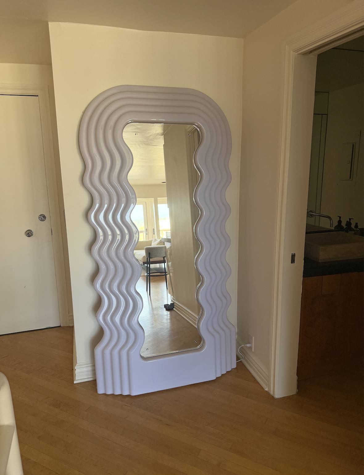 A wavy-edged full-length mirror in the hallway