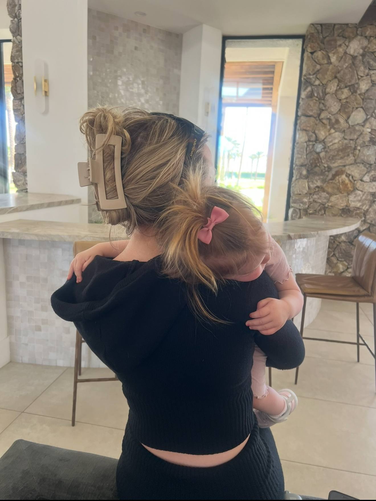 Holding a small child indoors, stone wall and tall windows behind