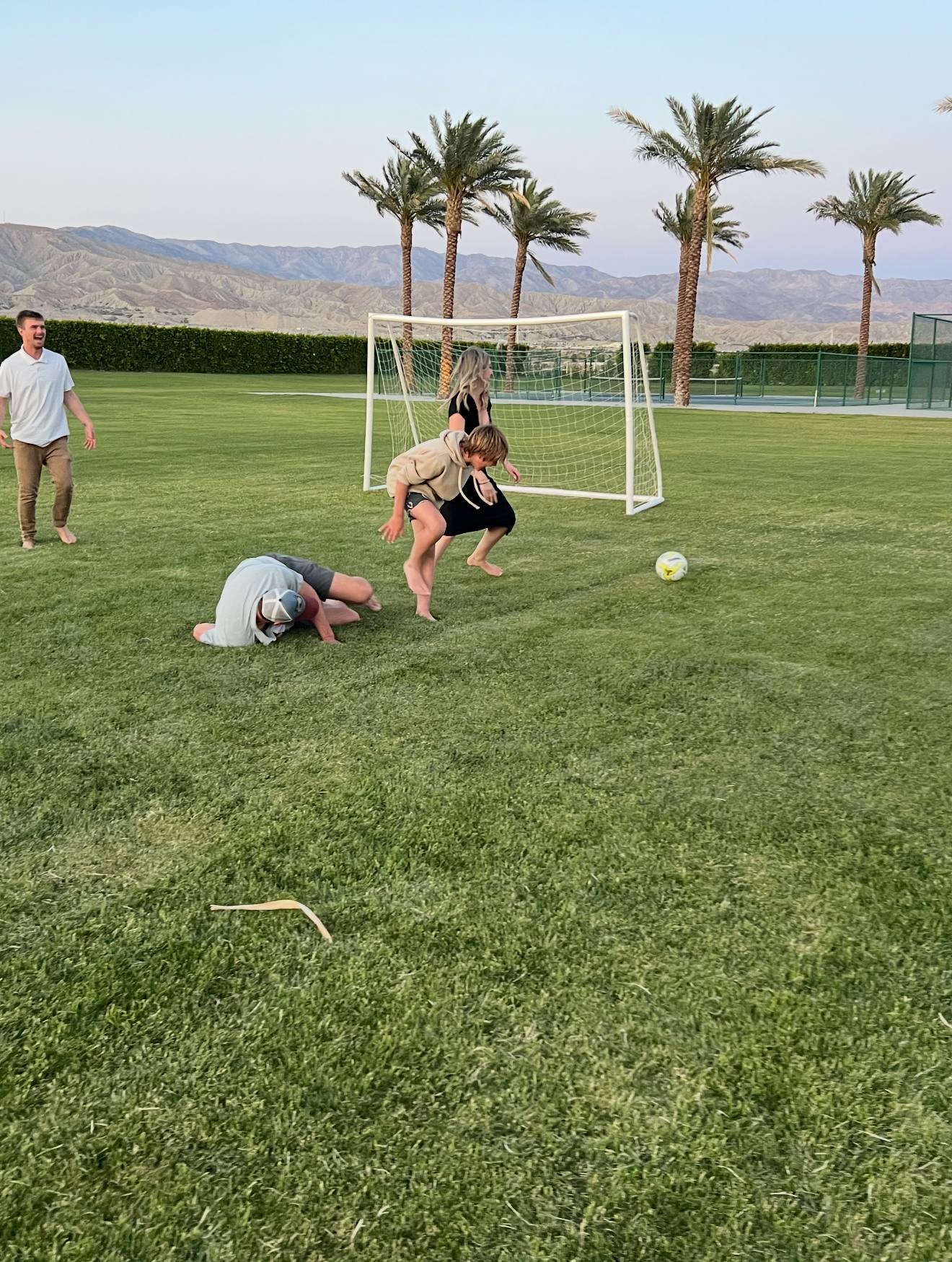 A football game on the lawn between the palms