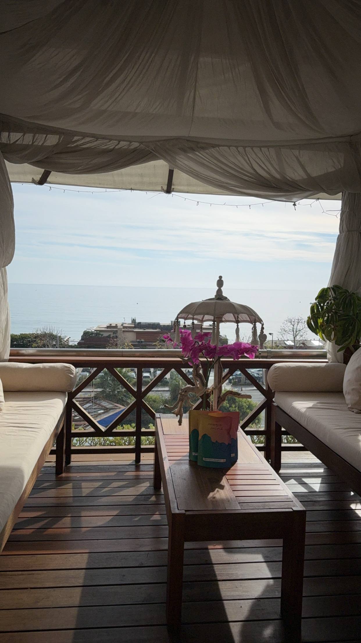 A timber lounge deck with flowers, looking out over the hills