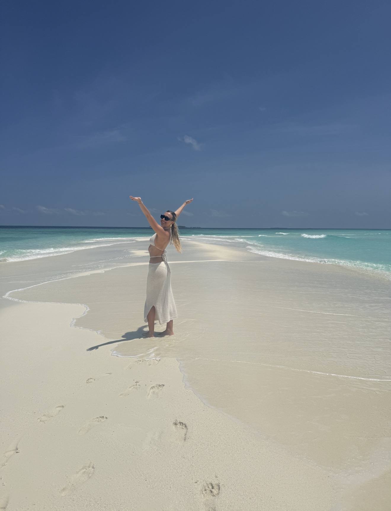 Lauren, arms up, alone on a Maldives sandbank