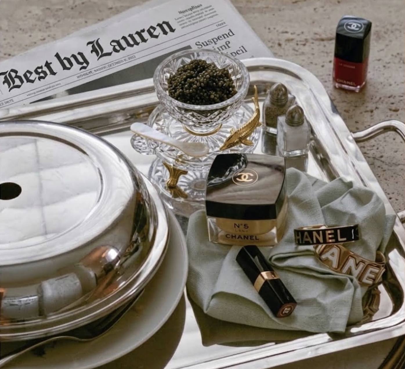 Silver tray with caviar, Chanel lipstick and a Best by Lauren newspaper
