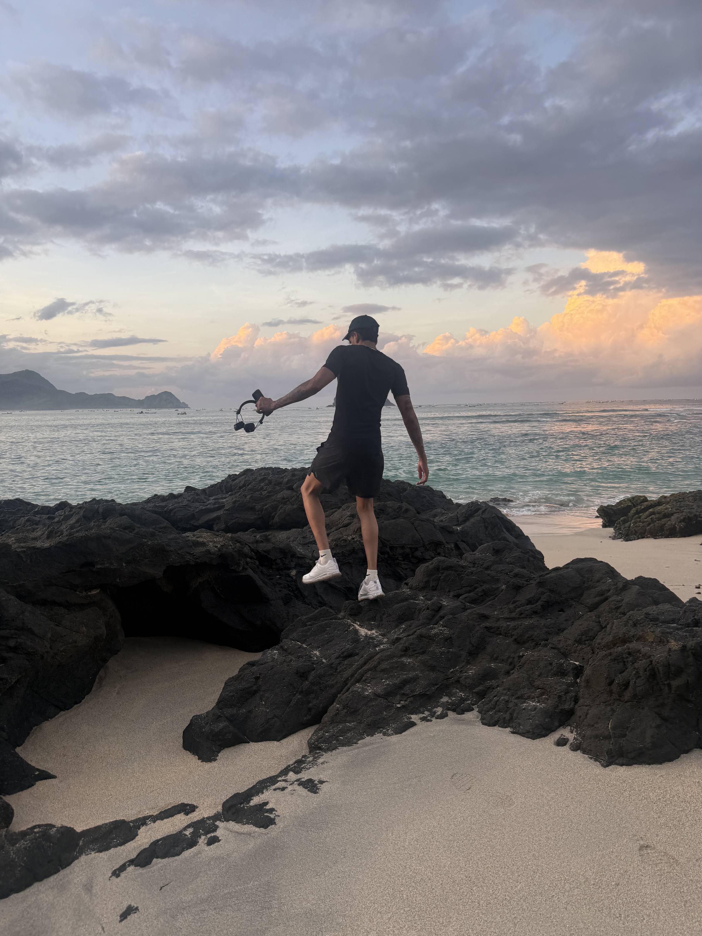 Standing on black rocks at sunrise, fishing rod out