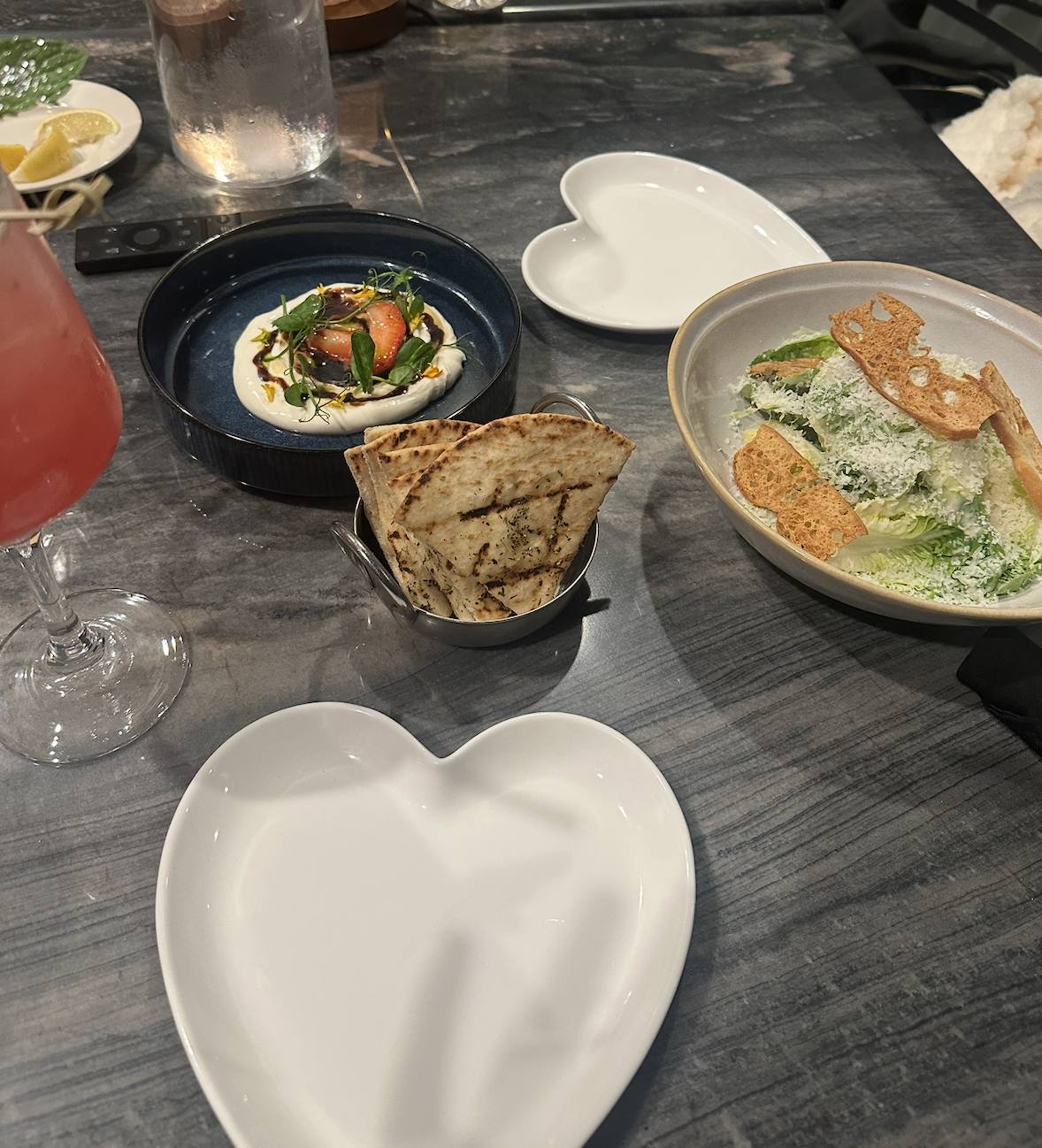 Small plates and a cocktail on a table, heart-shaped dish