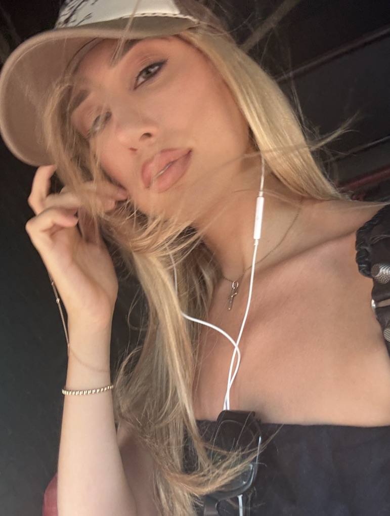 Close portrait in a pale trucker cap, hand to the hair